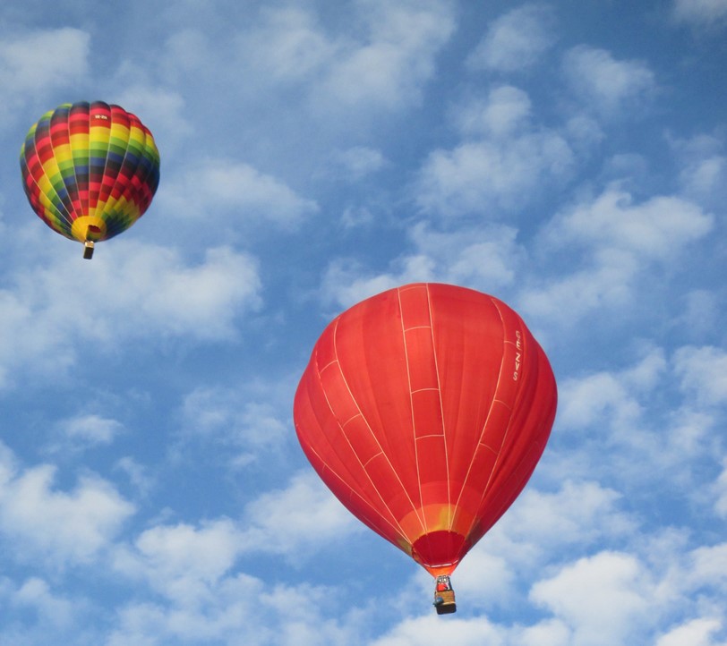 Två ballonger mot blå himmel och vita moln